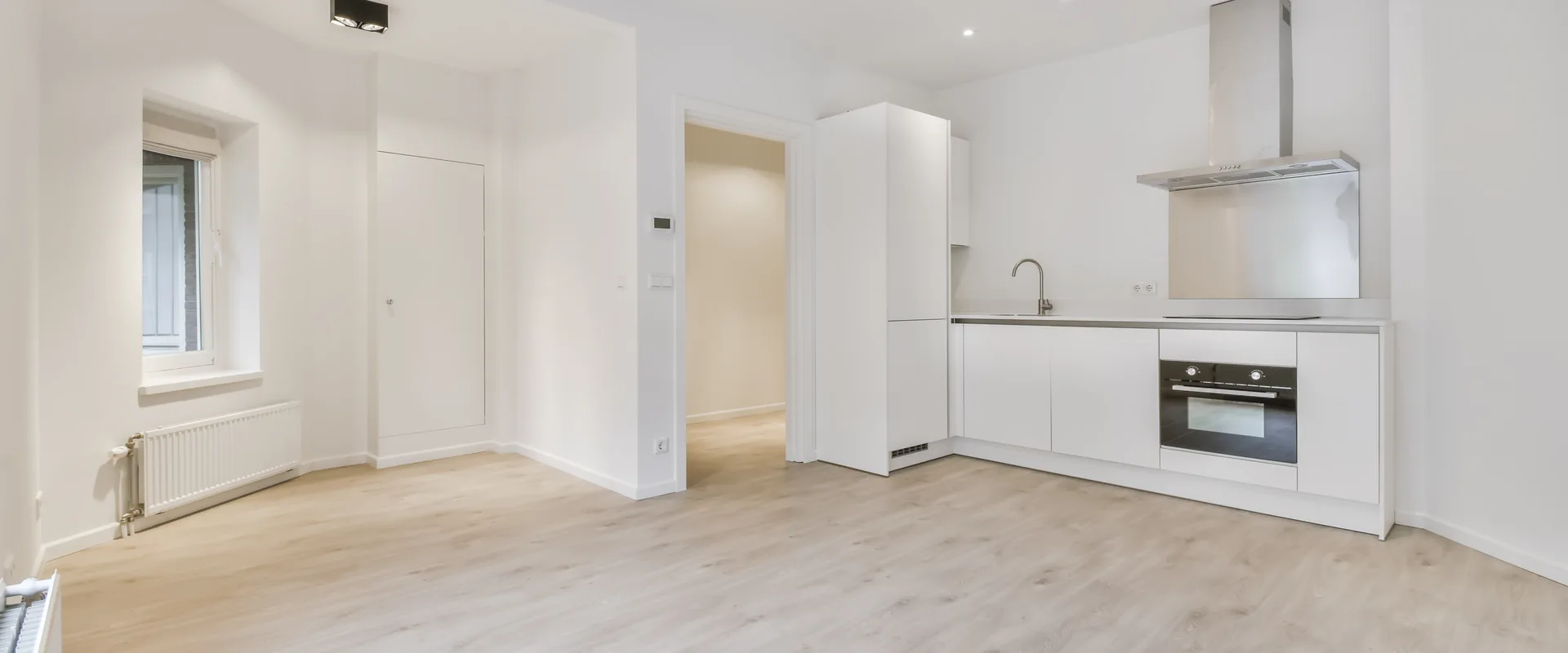 Bright updated apartment interior with modern kitchenette and wood-look flooring