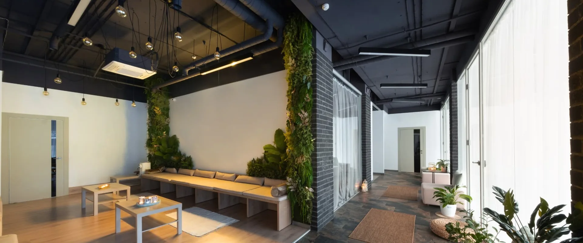 Modern commercial lounge interior with living green walls, exposed ceiling and bench seating