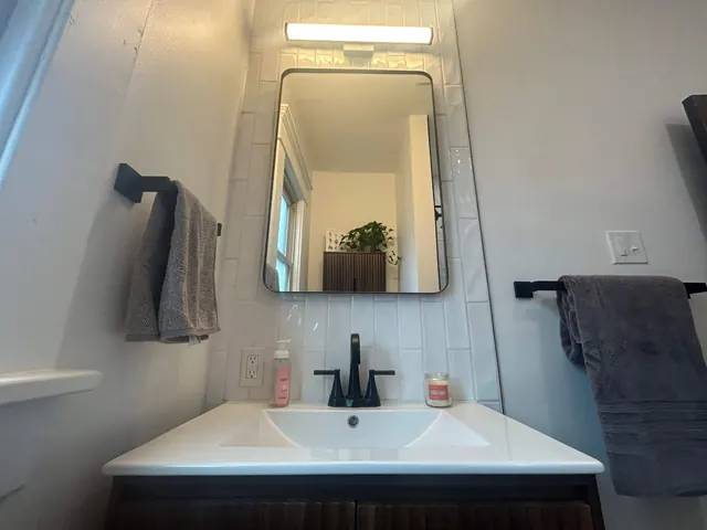 Bathroom sink with black fixtures and framed mirror