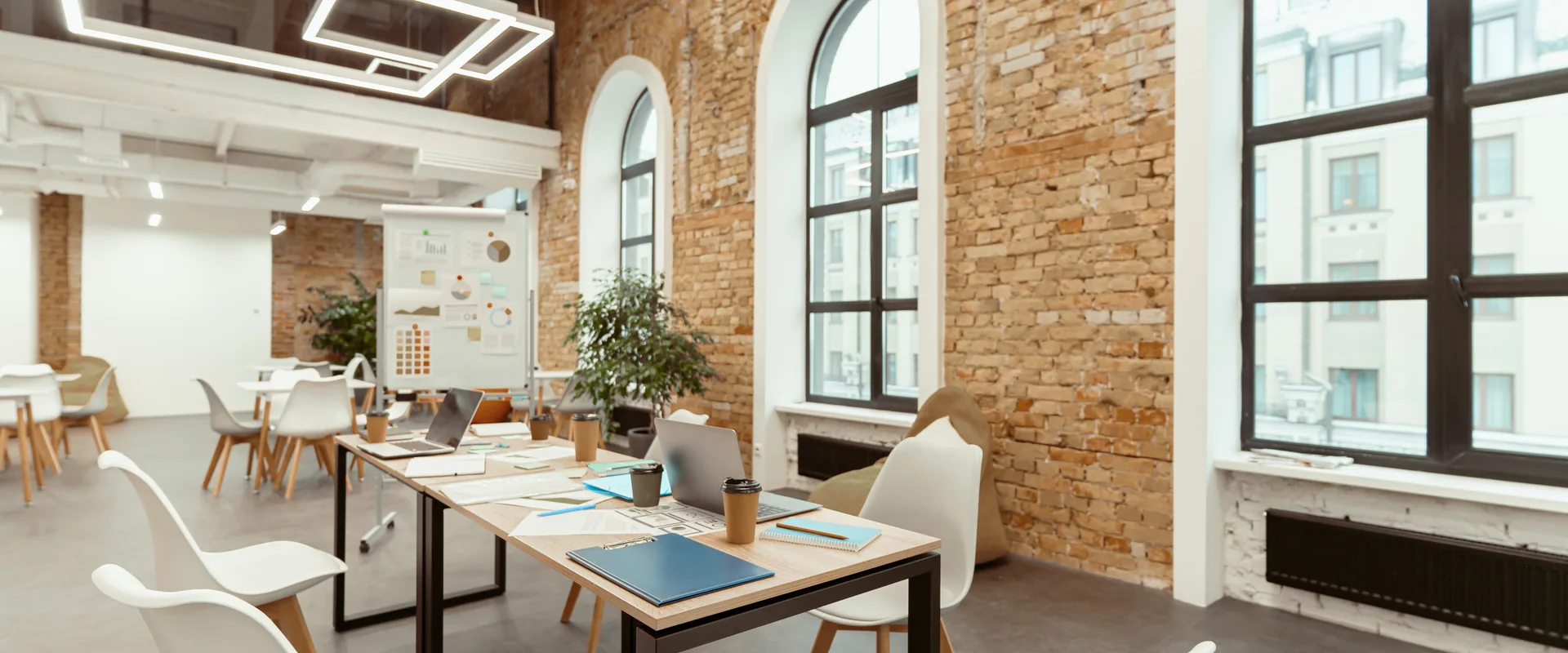 Renovated commercial office with exposed brick, tall windows and work tables